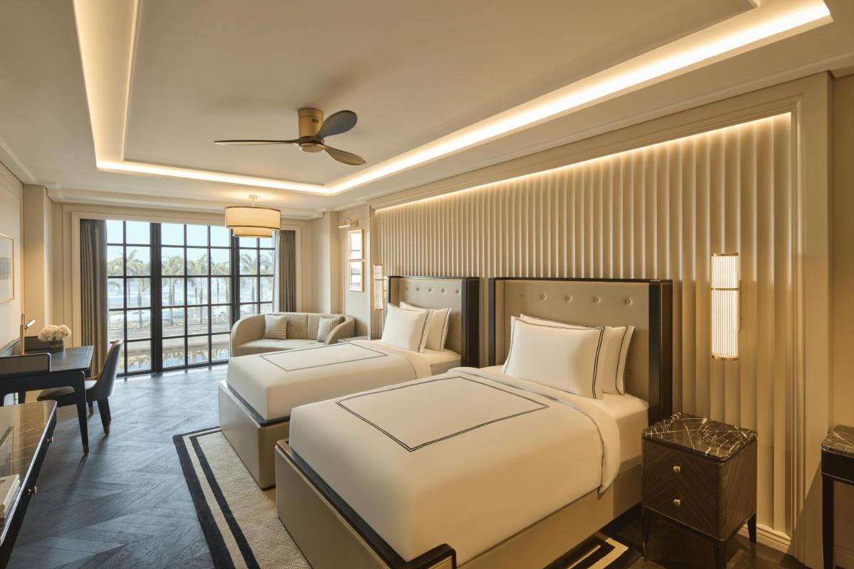 a bedroom with two beds and a desk and a couch at Fairmont Mumbai in Mumbai