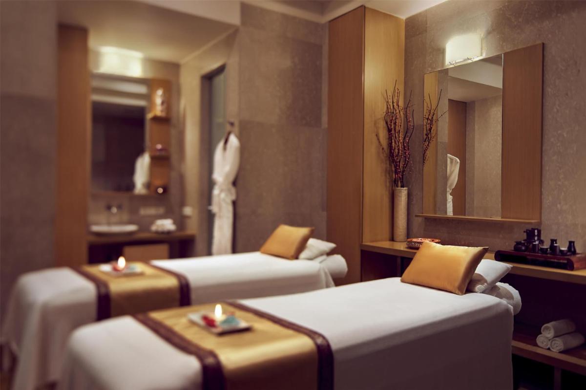 a hotel room with three beds and a mirror at Grand Hyatt Mumbai Hotel and Residences in Mumbai