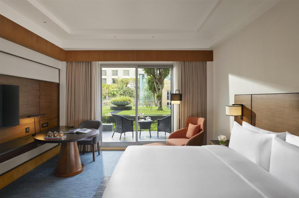 a hotel room with a bed and a table with chairs at Grand Hyatt Mumbai Hotel and Residences in Mumbai