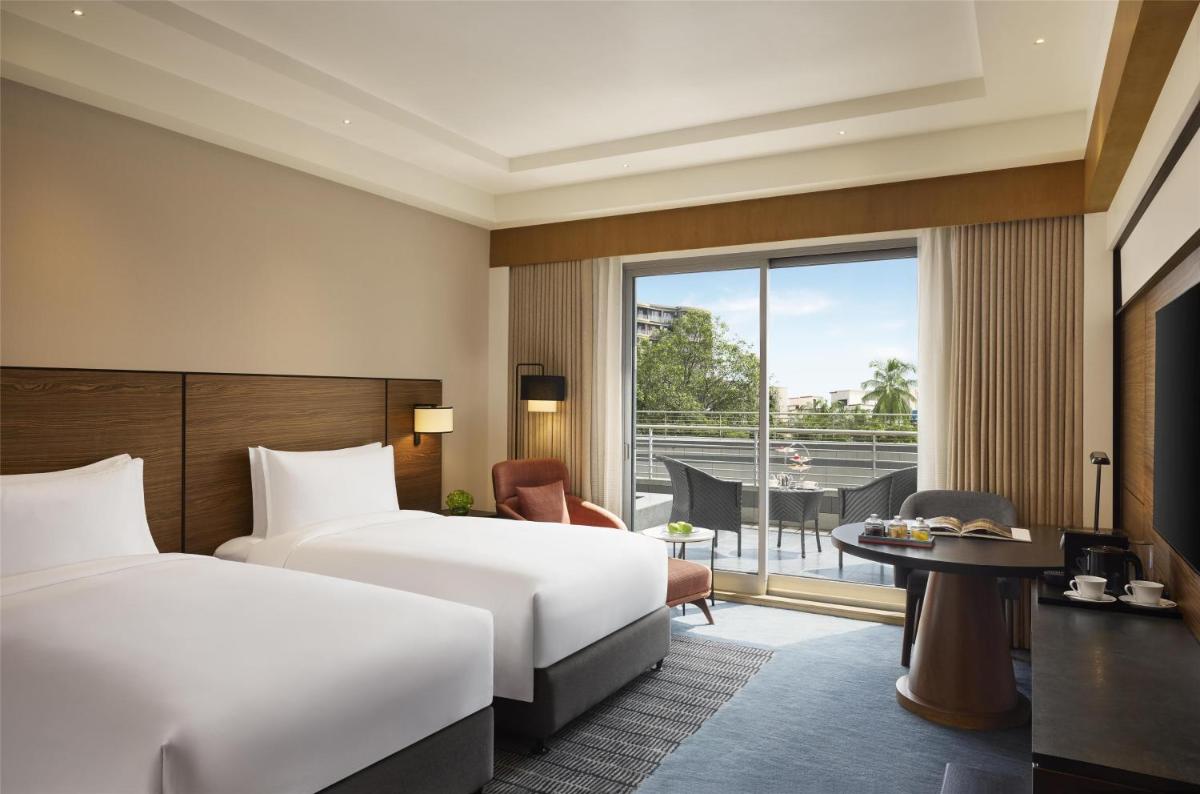 a hotel room with two beds and a balcony at Grand Hyatt Mumbai Hotel and Residences in Mumbai