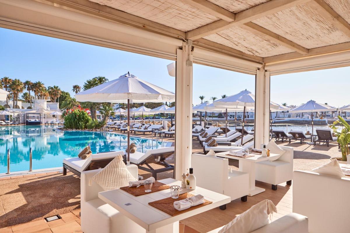 Un patio al aire libre con mesas y sillas y una piscina. en AluaSoul Menorca - Adults Only, en S'Algar