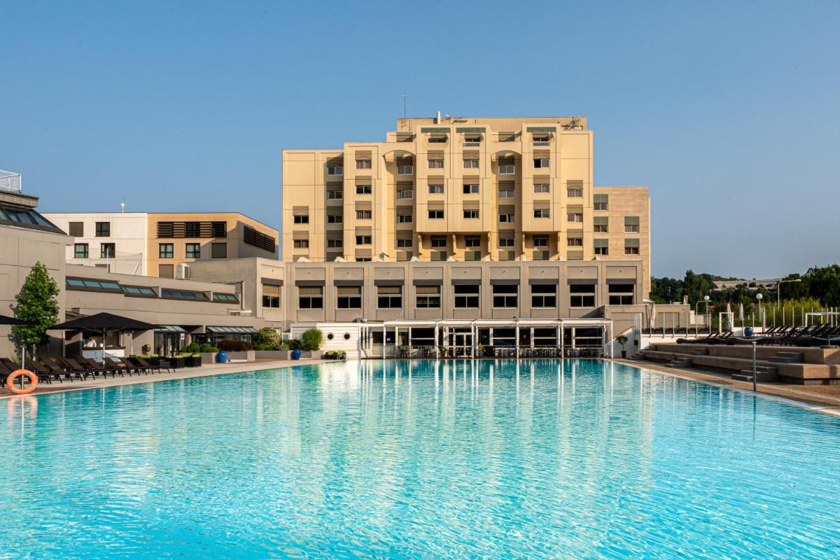une grande piscine d'eau devant un bâtiment dans l'établissement Hôtel Lyon Métropole & Spa, à Lyon