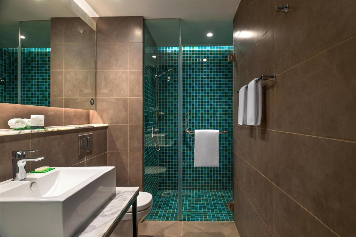 a bathroom with a shower with a sink and a toilet at Hyatt Centric Candolim Goa in Calangute a bathroom with a shower with a sink and a toilet at Hyatt Centric Candolim Goa in Calangute