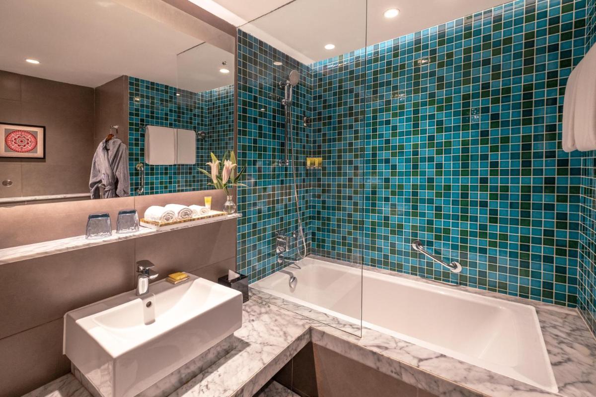 a bathroom with a tub and a sink and a bath tub at Hyatt Centric Candolim Goa in Calangute a bathroom with a tub and a sink and a bath tub at Hyatt Centric Candolim Goa in Calangute