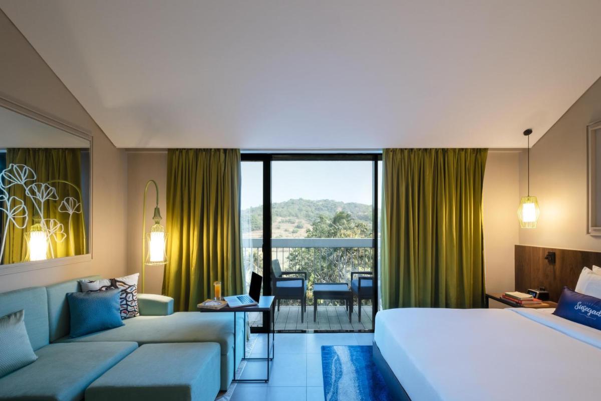 a hotel room with a bed and a couch at Hyatt Centric Candolim Goa in Calangute a hotel room with a bed and a couch at Hyatt Centric Candolim Goa in Calangute