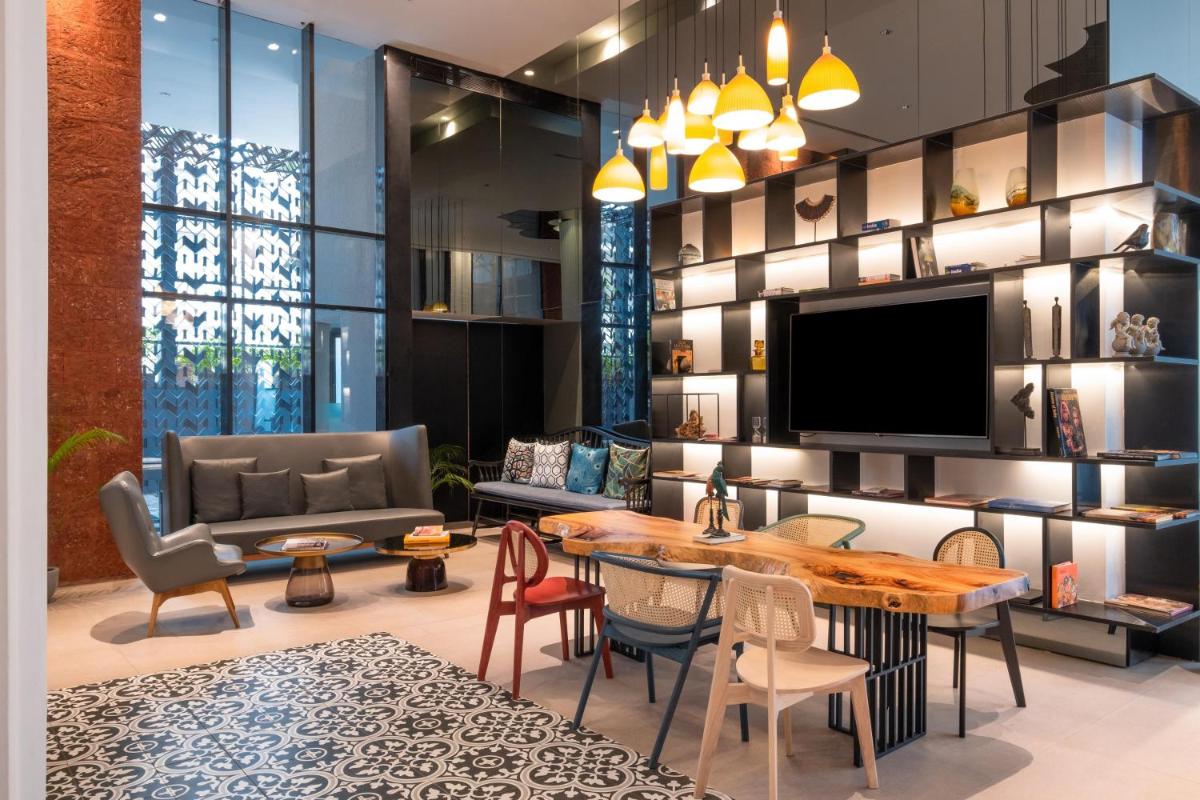 a living room with a tv and a table and chairs at Hyatt Centric Candolim Goa in Calangute a living room with a tv and a table and chairs at Hyatt Centric Candolim Goa in Calangute