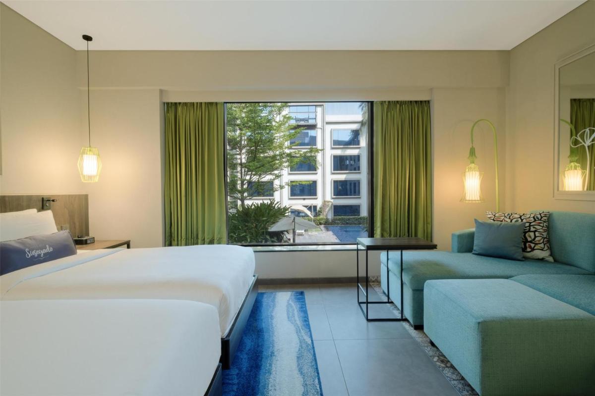 a bedroom with a bed and a couch and a window at Hyatt Centric Candolim Goa in Calangute a bedroom with a bed and a couch and a window at Hyatt Centric Candolim Goa in Calangute