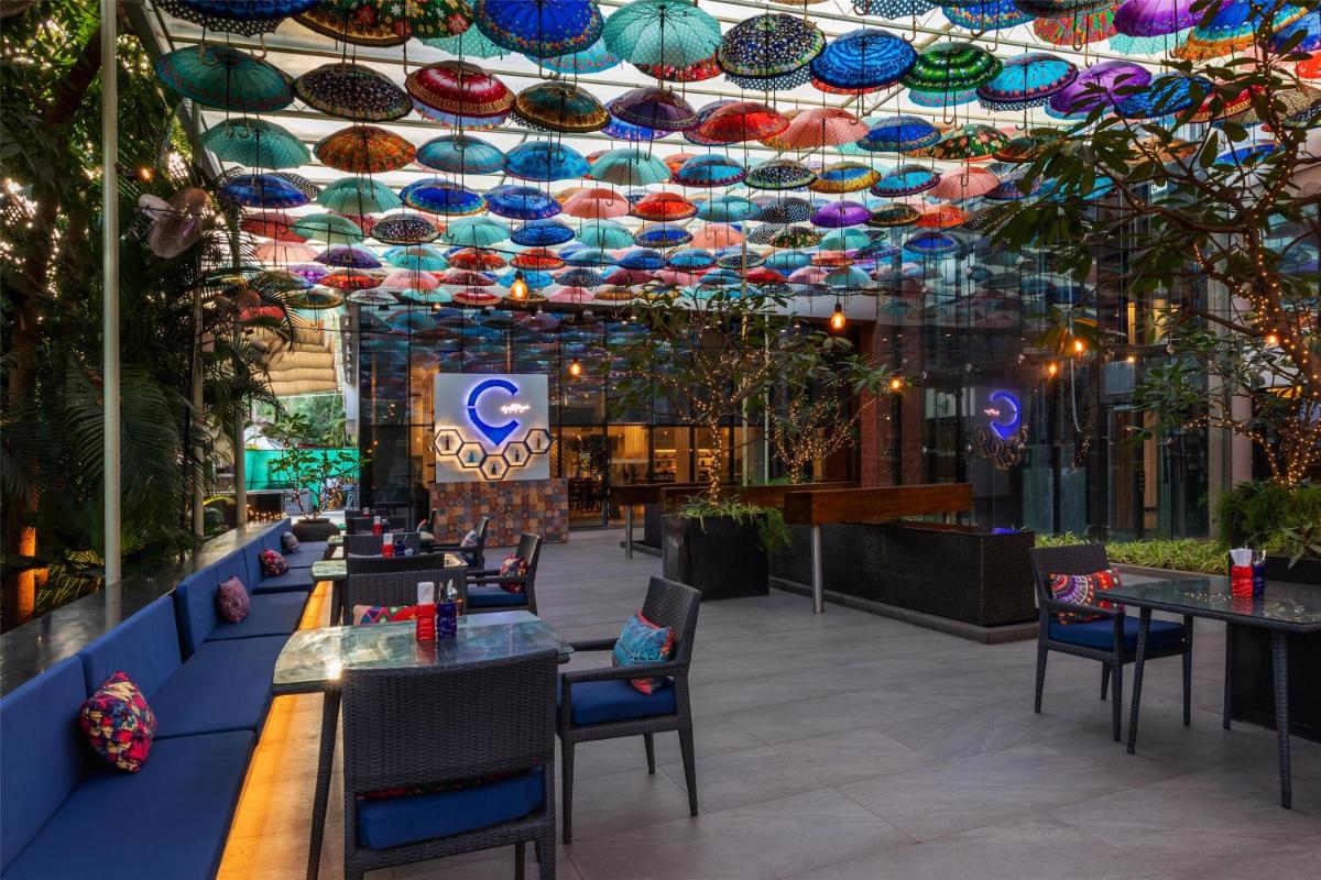 a restaurant with tables and chairs and a ceiling with umbrellas at Hyatt Centric Candolim Goa in Calangute a restaurant with tables and chairs and a ceiling with umbrellas at Hyatt Centric Candolim Goa in Calangute