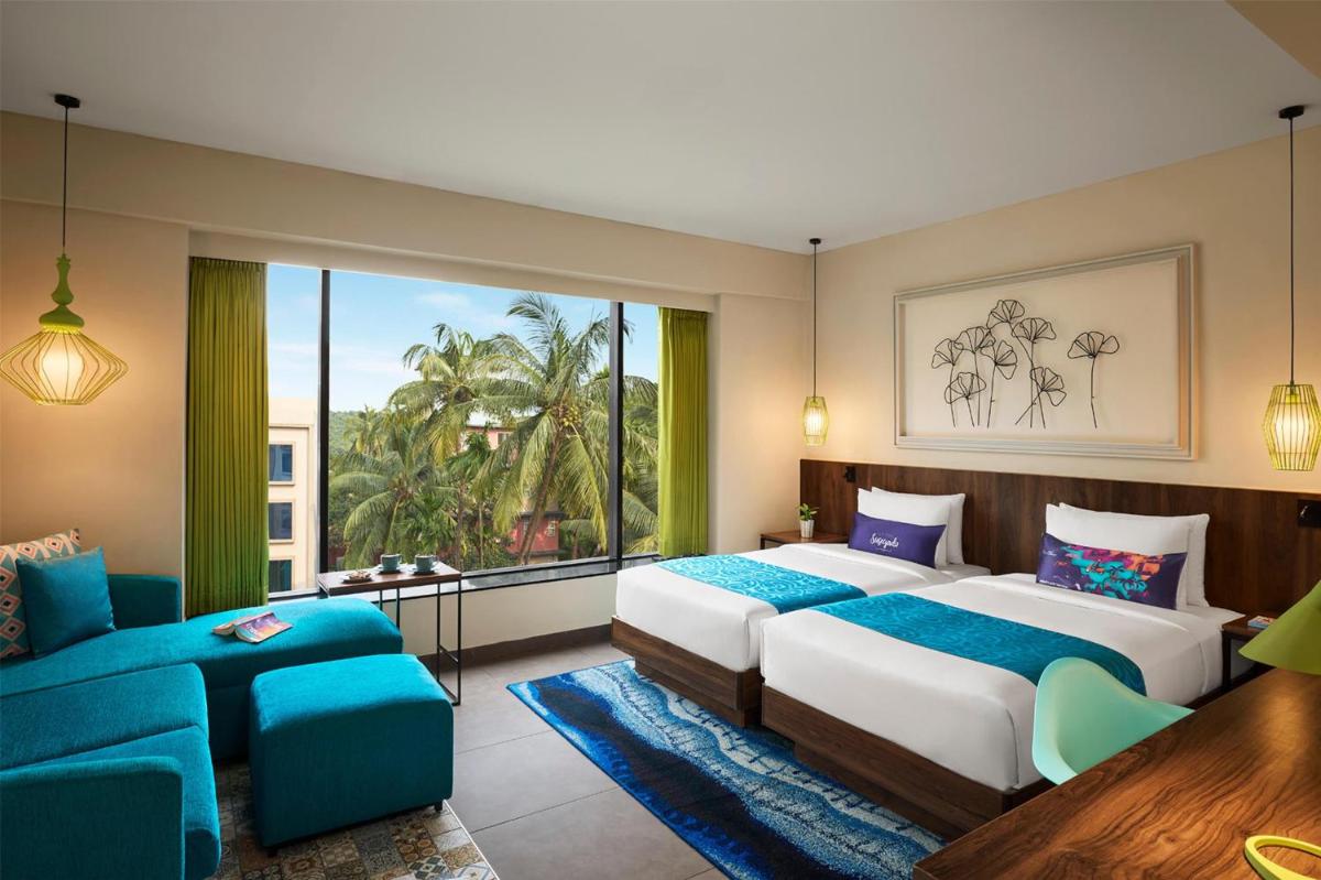two beds in a room with a large window at Hyatt Centric Candolim Goa in Calangute two beds in a room with a large window at Hyatt Centric Candolim Goa in Calangute