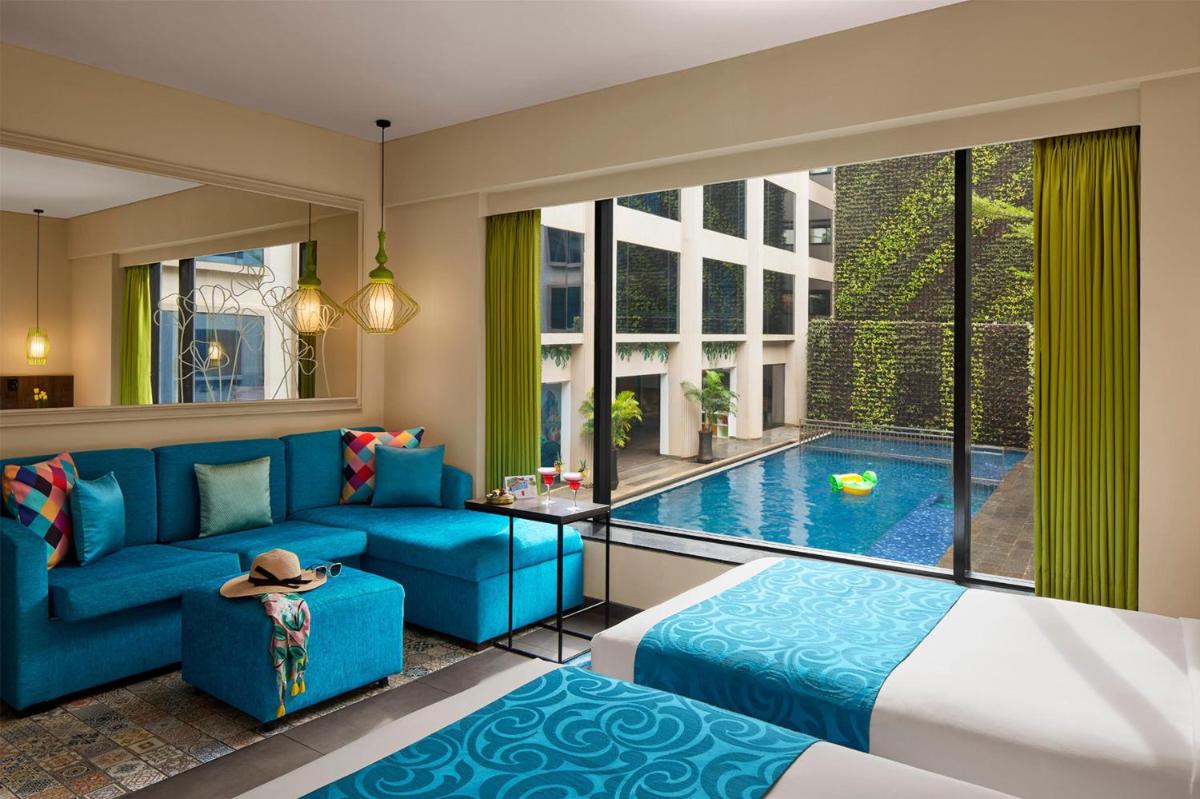 a living room with a blue couch and a swimming pool at Hyatt Centric Candolim Goa in Calangute a living room with a blue couch and a swimming pool at Hyatt Centric Candolim Goa in Calangute