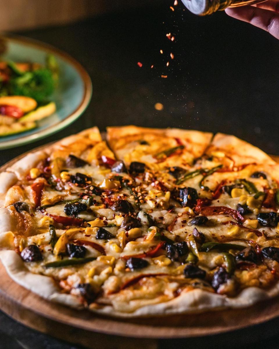 a pizza sitting on top of a wooden table at Hyatt Centric Candolim Goa in Calangute a pizza sitting on top of a wooden table at Hyatt Centric Candolim Goa in Calangute