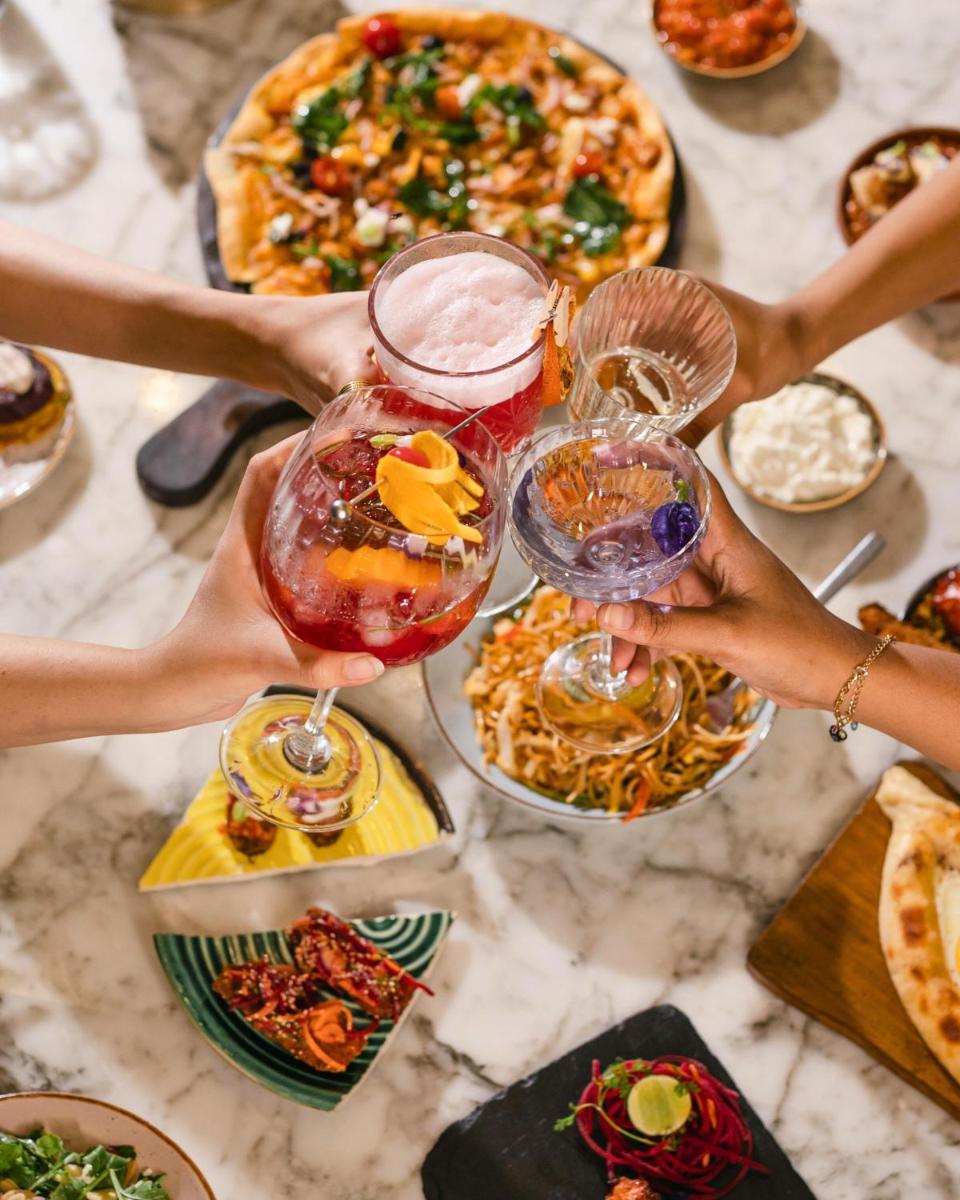 a group of people holding up glasses on a table with food at Hyatt Centric Candolim Goa in Calangute a group of people holding up glasses on a table with food at Hyatt Centric Candolim Goa in Calangute