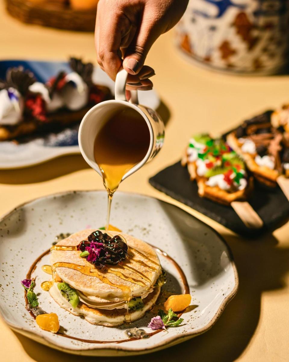 a person is pouring syrup onto a plate of pancakes at Hyatt Centric Candolim Goa in Calangute a person is pouring syrup onto a plate of pancakes at Hyatt Centric Candolim Goa in Calangute