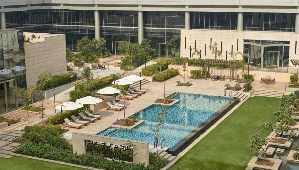 an aerial view of a building with a swimming pool at Andaz Delhi, by Hyatt in New Delhi an aerial view of a building with a swimming pool at Andaz Delhi, by Hyatt in New Delhi