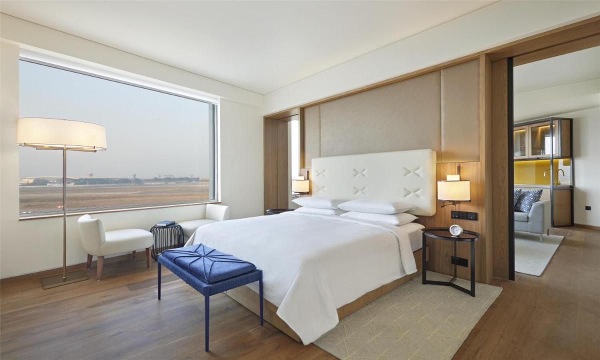 a bedroom with a large bed and a large window at Andaz Delhi, by Hyatt in New Delhi a bedroom with a large bed and a large window at Andaz Delhi, by Hyatt in New Delhi