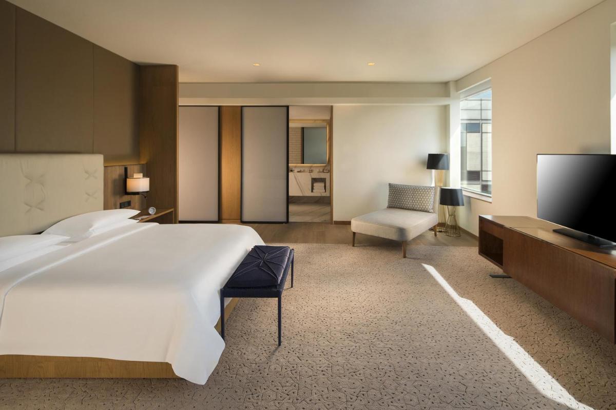 a large bedroom with a large bed and a television at Andaz Delhi, by Hyatt in New Delhi a large bedroom with a large bed and a television at Andaz Delhi, by Hyatt in New Delhi