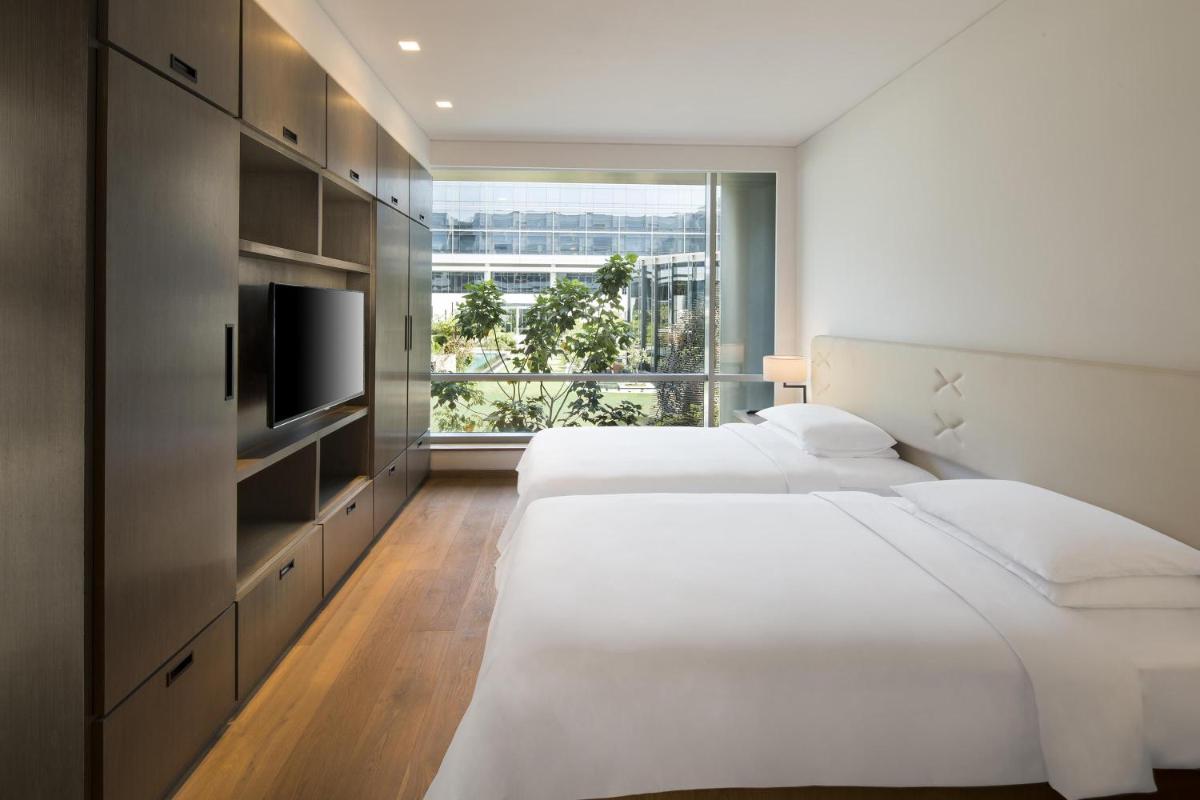 a bedroom with two beds and a tv and a window at Andaz Delhi, by Hyatt in New Delhi a bedroom with two beds and a tv and a window at Andaz Delhi, by Hyatt in New Delhi