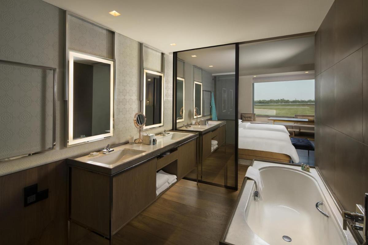 a bathroom with three sinks and a tub and a bed at Andaz Delhi, by Hyatt in New Delhi a bathroom with three sinks and a tub and a bed at Andaz Delhi, by Hyatt in New Delhi
