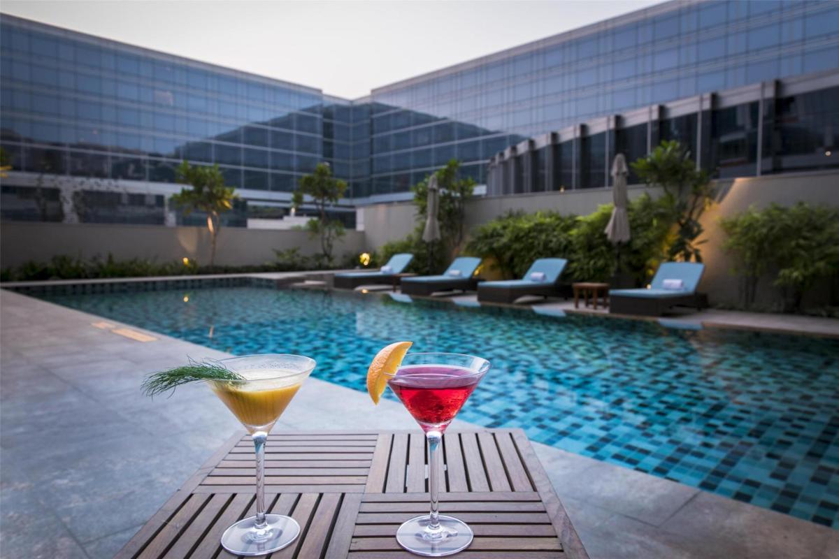 two cocktails on a table next to a swimming pool at Andaz Delhi, by Hyatt in New Delhi two cocktails on a table next to a swimming pool at Andaz Delhi, by Hyatt in New Delhi