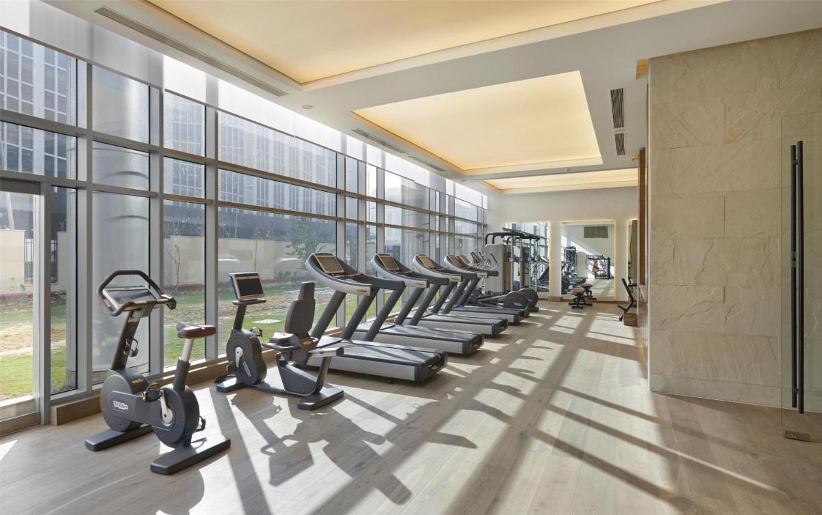 a gym with a row of treadmills and ellipticals at Andaz Delhi, by Hyatt in New Delhi a gym with a row of treadmills and ellipticals at Andaz Delhi, by Hyatt in New Delhi