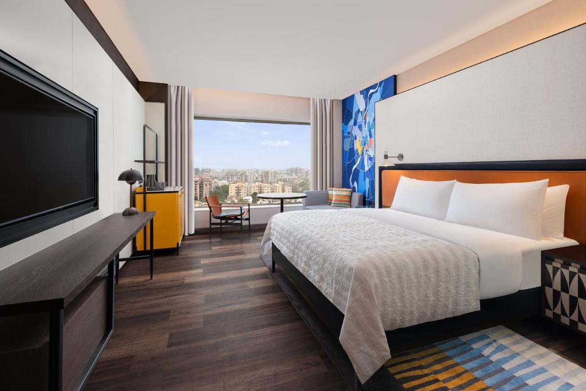 a hotel room with a bed and a flat screen tv at Le Meridien Ahmedabad in Ahmedabad
