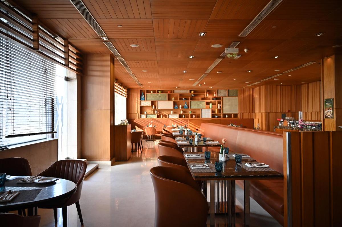 a dining room with tables and chairs in a restaurant at Holiday Inn New Delhi Mayur Vihar Noida by IHG in New Delhi a dining room with tables and chairs in a restaurant at Holiday Inn New Delhi Mayur Vihar Noida by IHG in New Delhi