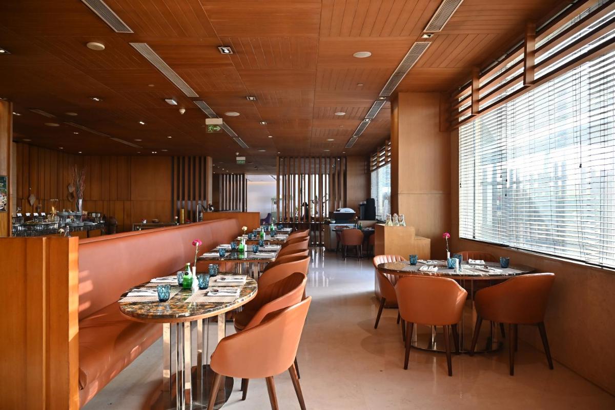 a restaurant with tables and chairs and a bar at Holiday Inn New Delhi Mayur Vihar Noida by IHG in New Delhi a restaurant with tables and chairs and a bar at Holiday Inn New Delhi Mayur Vihar Noida by IHG in New Delhi
