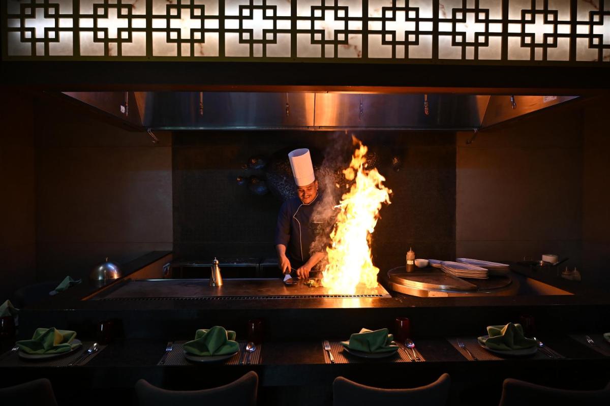 a chef cooking over a fire in a fireplace at Holiday Inn New Delhi Mayur Vihar Noida by IHG in New Delhi a chef cooking over a fire in a fireplace at Holiday Inn New Delhi Mayur Vihar Noida by IHG in New Delhi