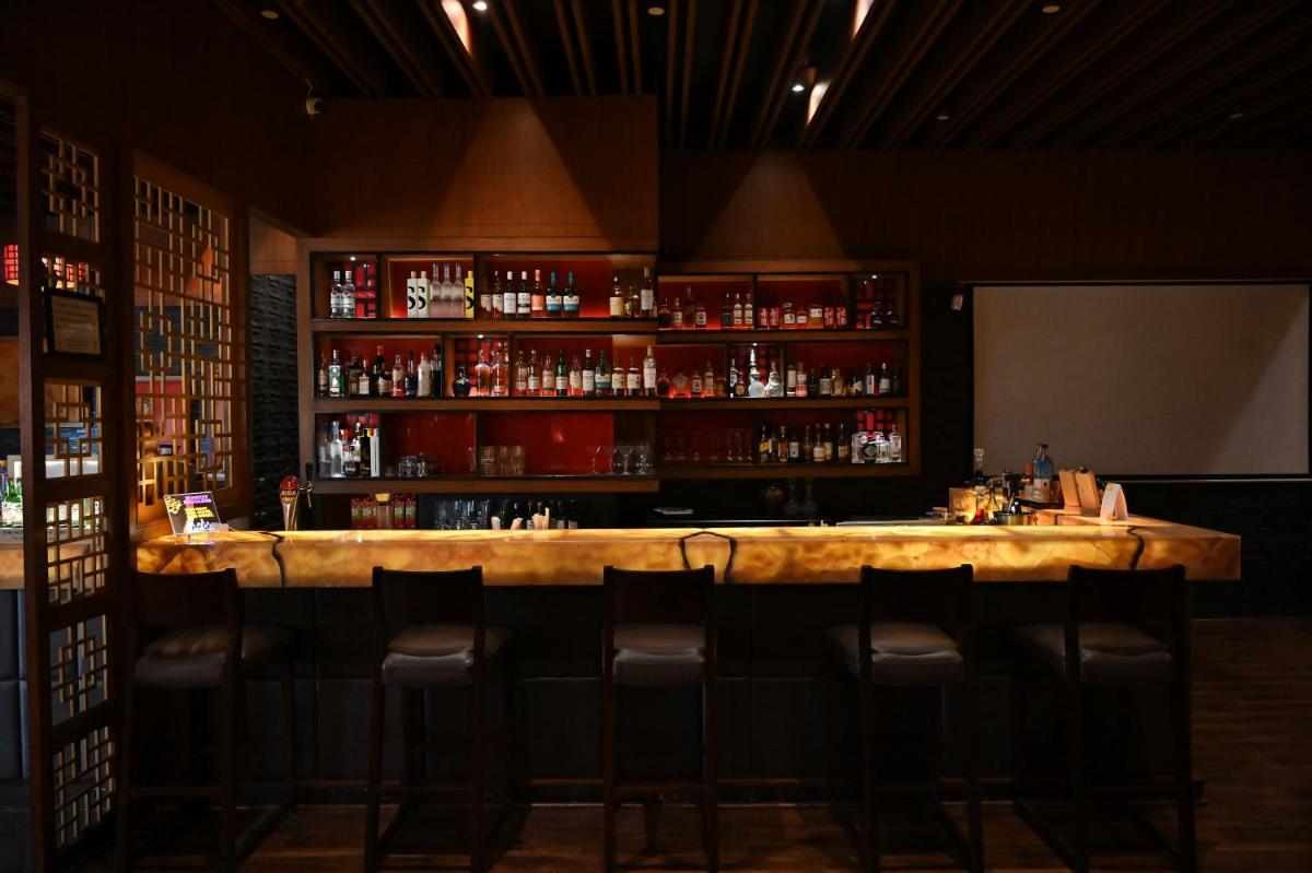 a bar with stools in a room with alcohol at Holiday Inn New Delhi Mayur Vihar Noida by IHG in New Delhi a bar with stools in a room with alcohol at Holiday Inn New Delhi Mayur Vihar Noida by IHG in New Delhi