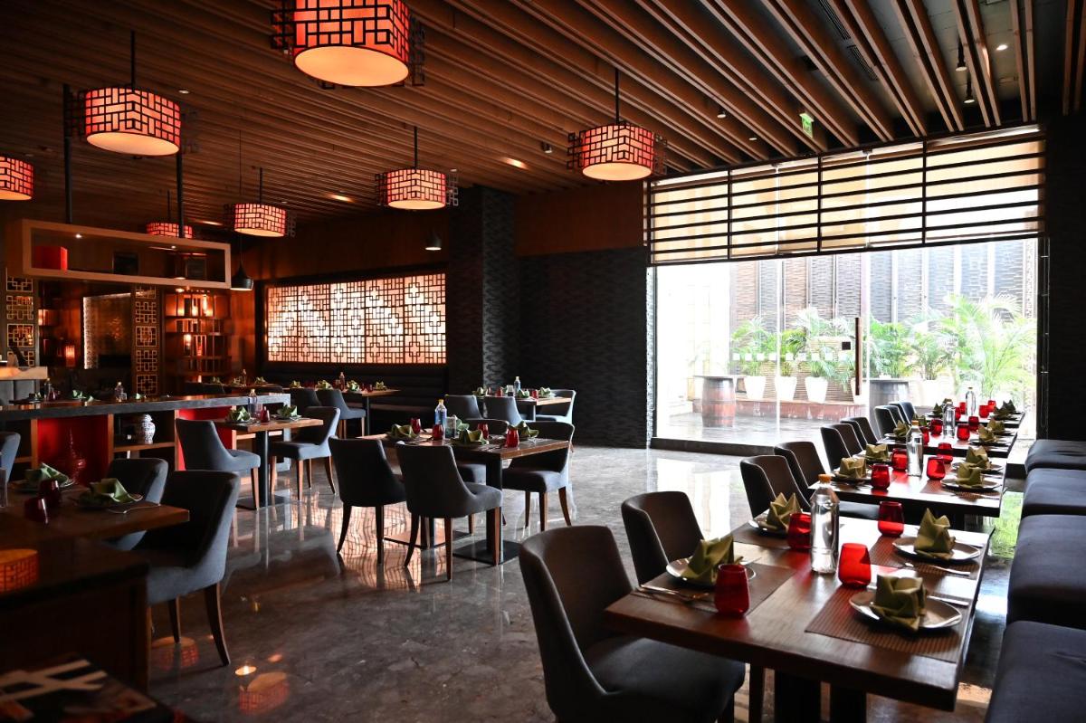 a dining room with tables and chairs in a restaurant at Holiday Inn New Delhi Mayur Vihar Noida by IHG in New Delhi a dining room with tables and chairs in a restaurant at Holiday Inn New Delhi Mayur Vihar Noida by IHG in New Delhi