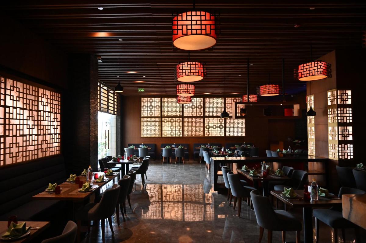 a dining room with tables and chairs and chandeliers at Holiday Inn New Delhi Mayur Vihar Noida by IHG in New Delhi a dining room with tables and chairs and chandeliers at Holiday Inn New Delhi Mayur Vihar Noida by IHG in New Delhi