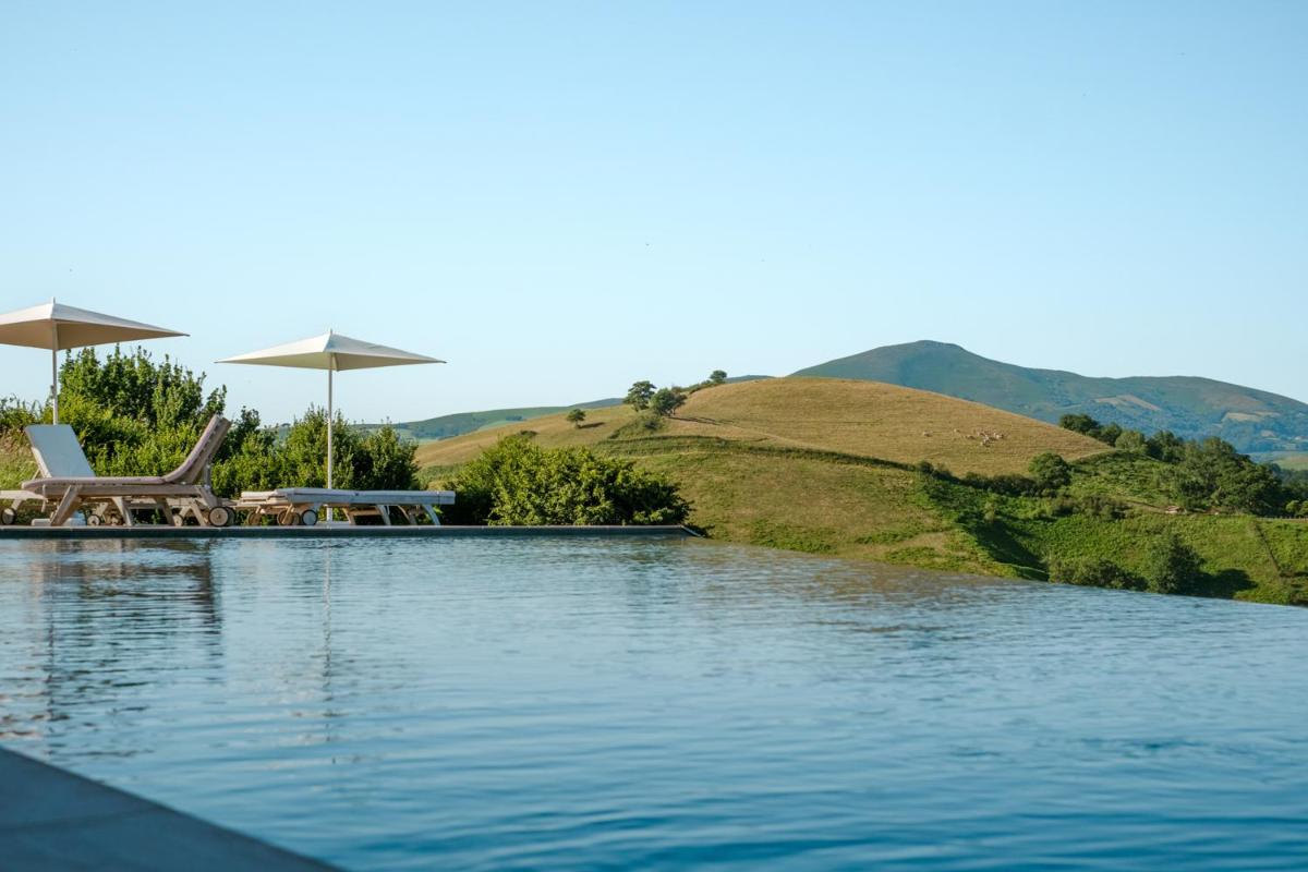 - une piscine avec des chaises et des parasols sur une colline dans l'établissement Auberge Ostapé, à Bidarray