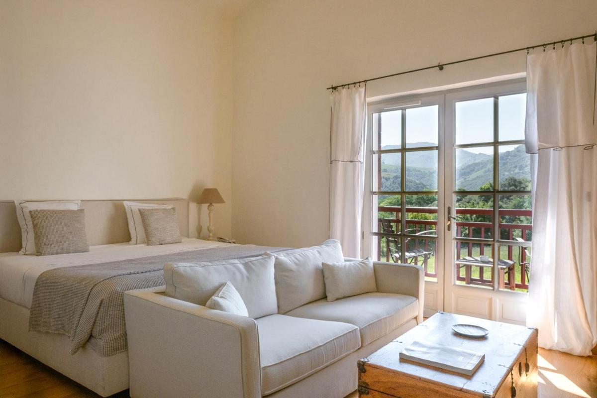 une chambre avec un lit, un canapé et une fenêtre dans l'établissement Auberge Ostapé, à Bidarray