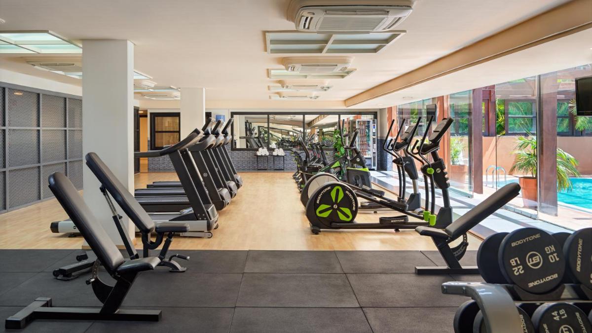 un gimnasio con una fila de cintas de correr y elípticas en H10 Costa Adeje Palace, en Adeje