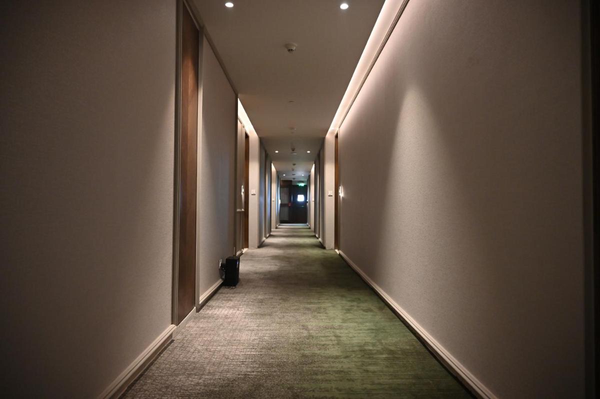 an empty hallway with a long corridor with a green carpet at Holiday Inn New Delhi Mayur Vihar Noida by IHG in New Delhi an empty hallway with a long corridor with a green carpet at Holiday Inn New Delhi Mayur Vihar Noida by IHG in New Delhi