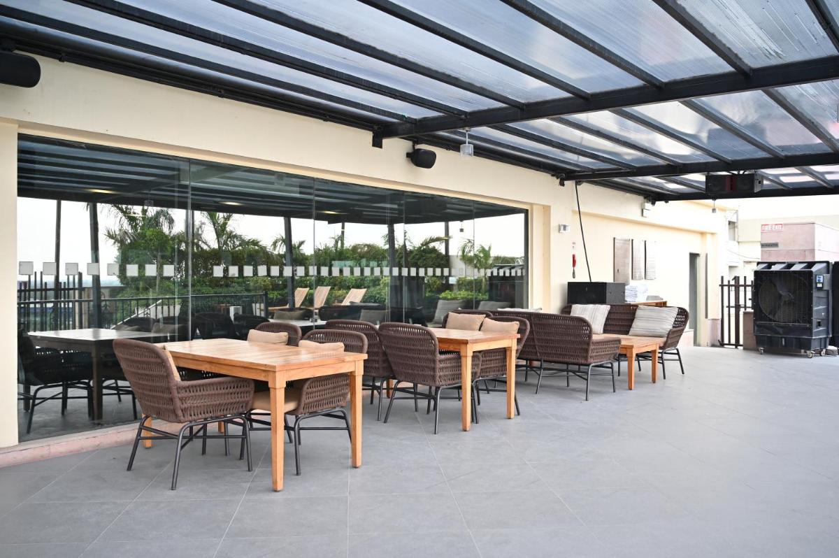 a patio with wooden tables and chairs and windows at Holiday Inn New Delhi Mayur Vihar Noida by IHG in New Delhi a patio with wooden tables and chairs and windows at Holiday Inn New Delhi Mayur Vihar Noida by IHG in New Delhi