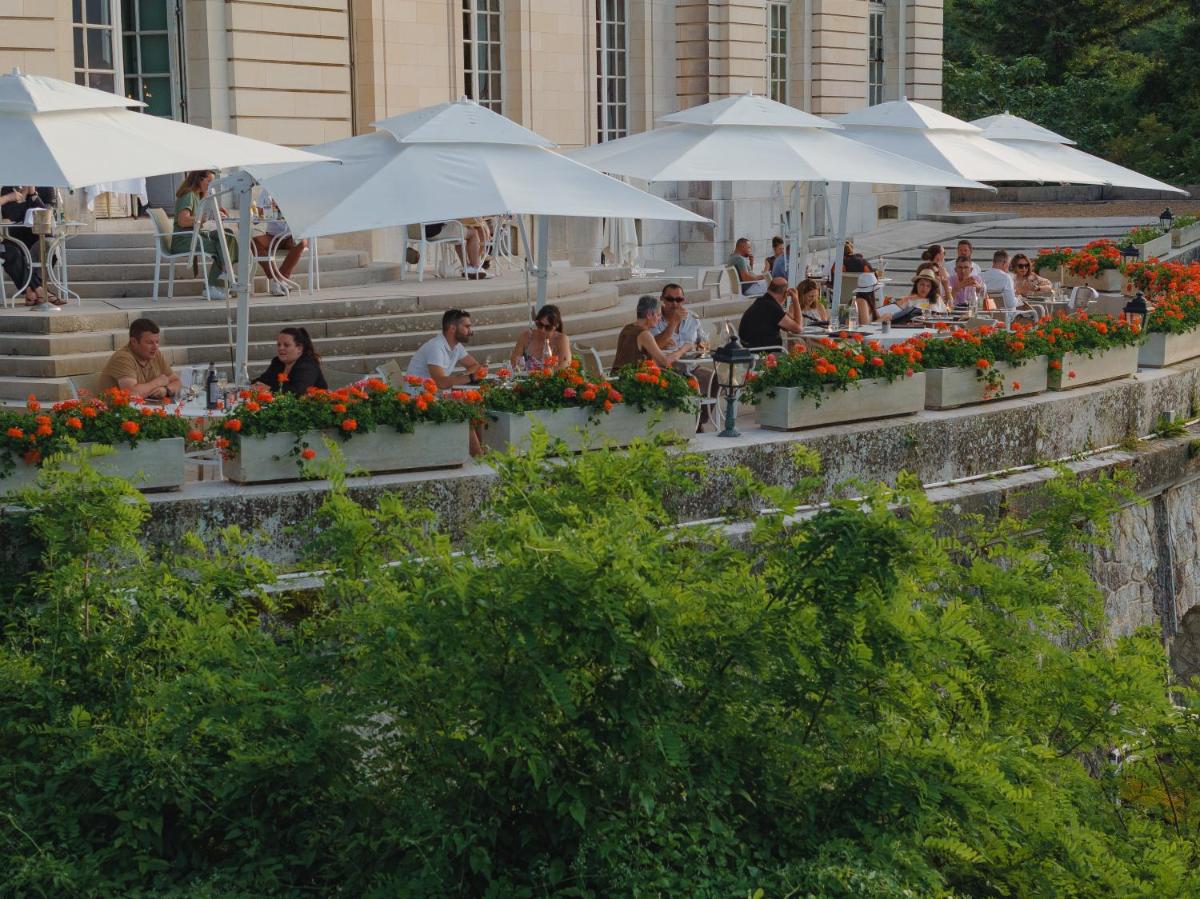 Un groupe de personnes assises à des tables sous des parasols dans l'établissement Château D'artigny, à Montbazon