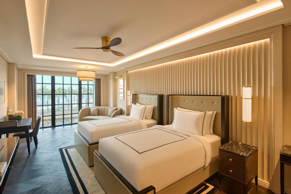 a hotel room with two beds and a desk at Fairmont Mumbai in Mumbai