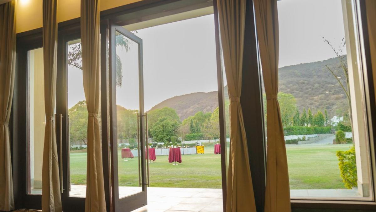an open glass door with a view of a golf course at DoubleTree By Hilton Jaipur Amer in Jaipur
