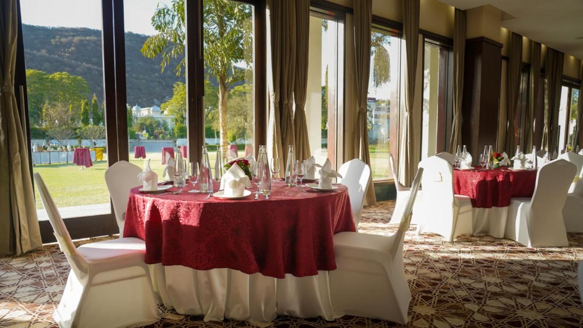 a dining room with tables and white chairs and windows at DoubleTree By Hilton Jaipur Amer in Jaipur