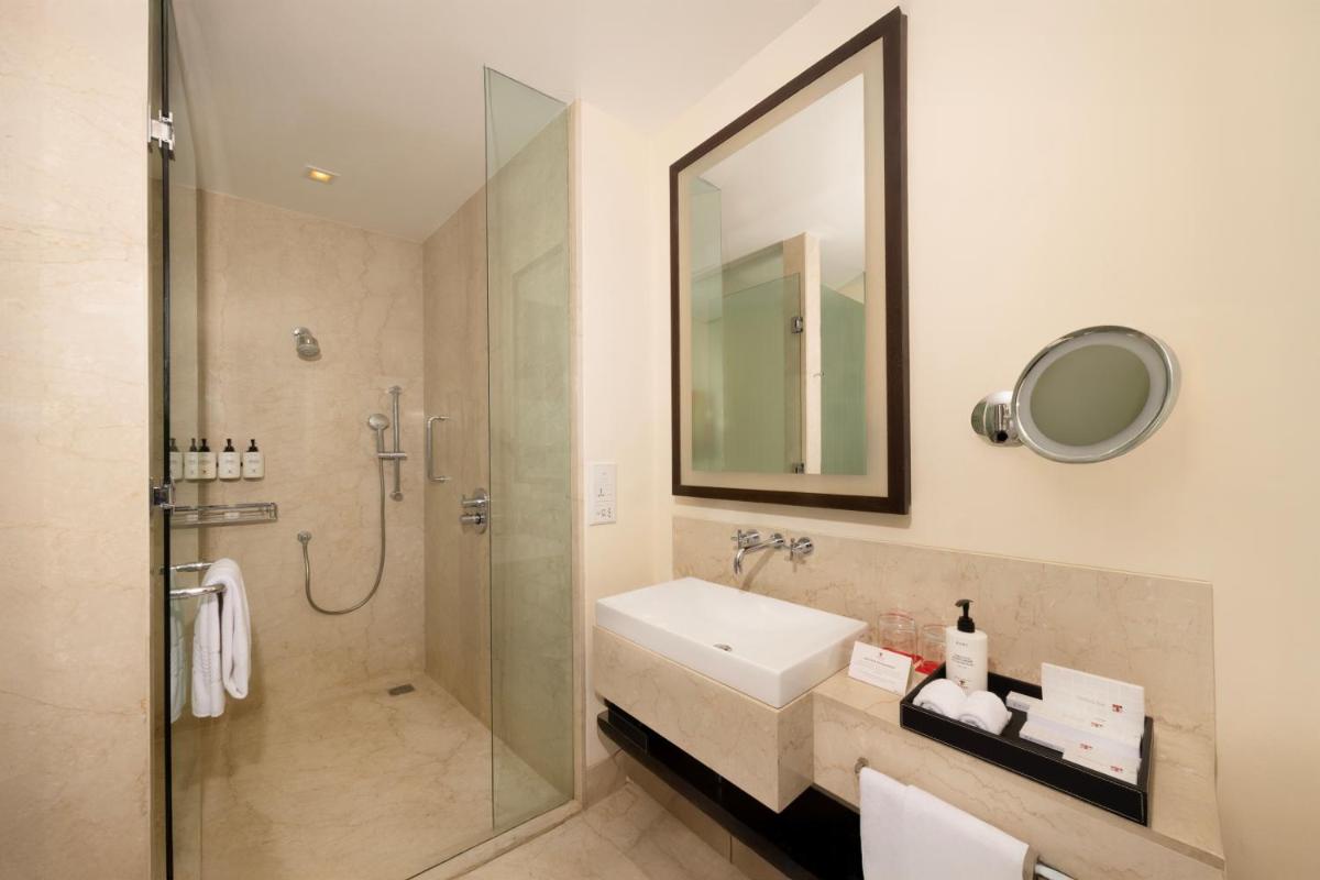 a bathroom with a shower and a sink and a mirror at Trident Hyderabad in Hyderabad