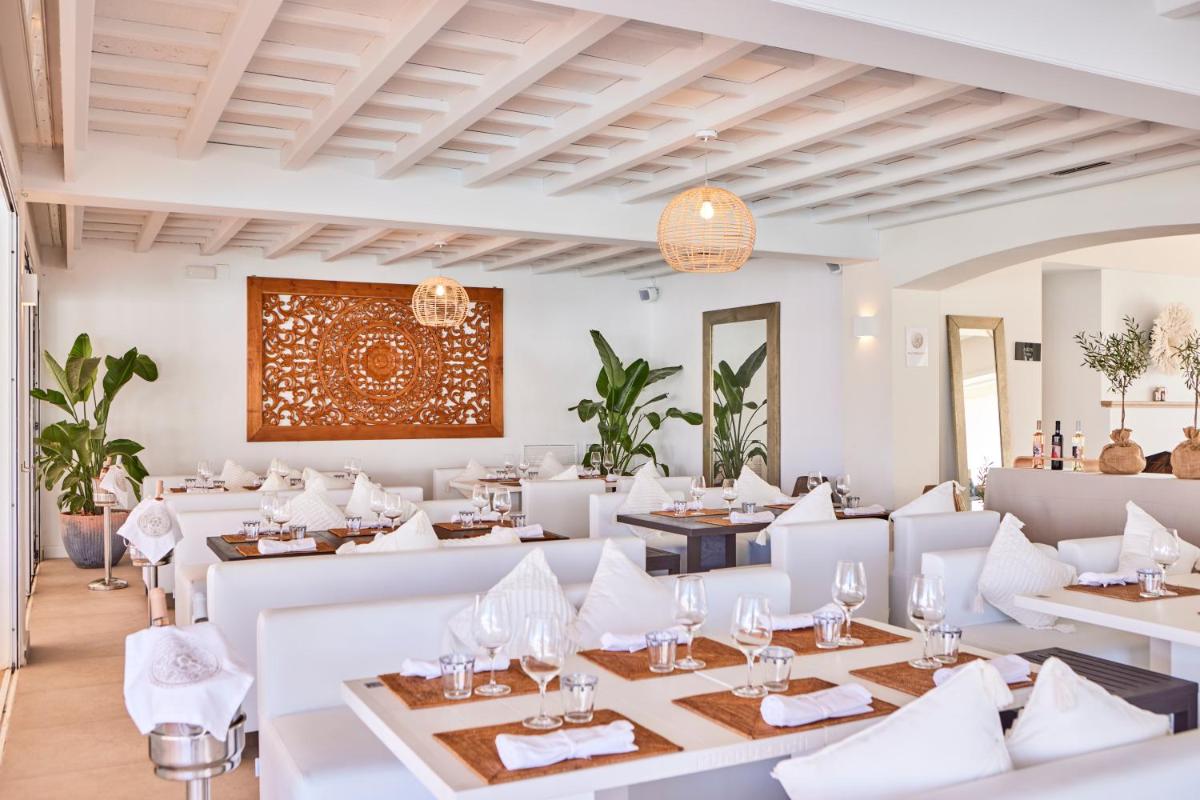 un restaurante con mesas blancas y sillas blancas en AluaSoul Menorca - Adults Only, en S'Algar
