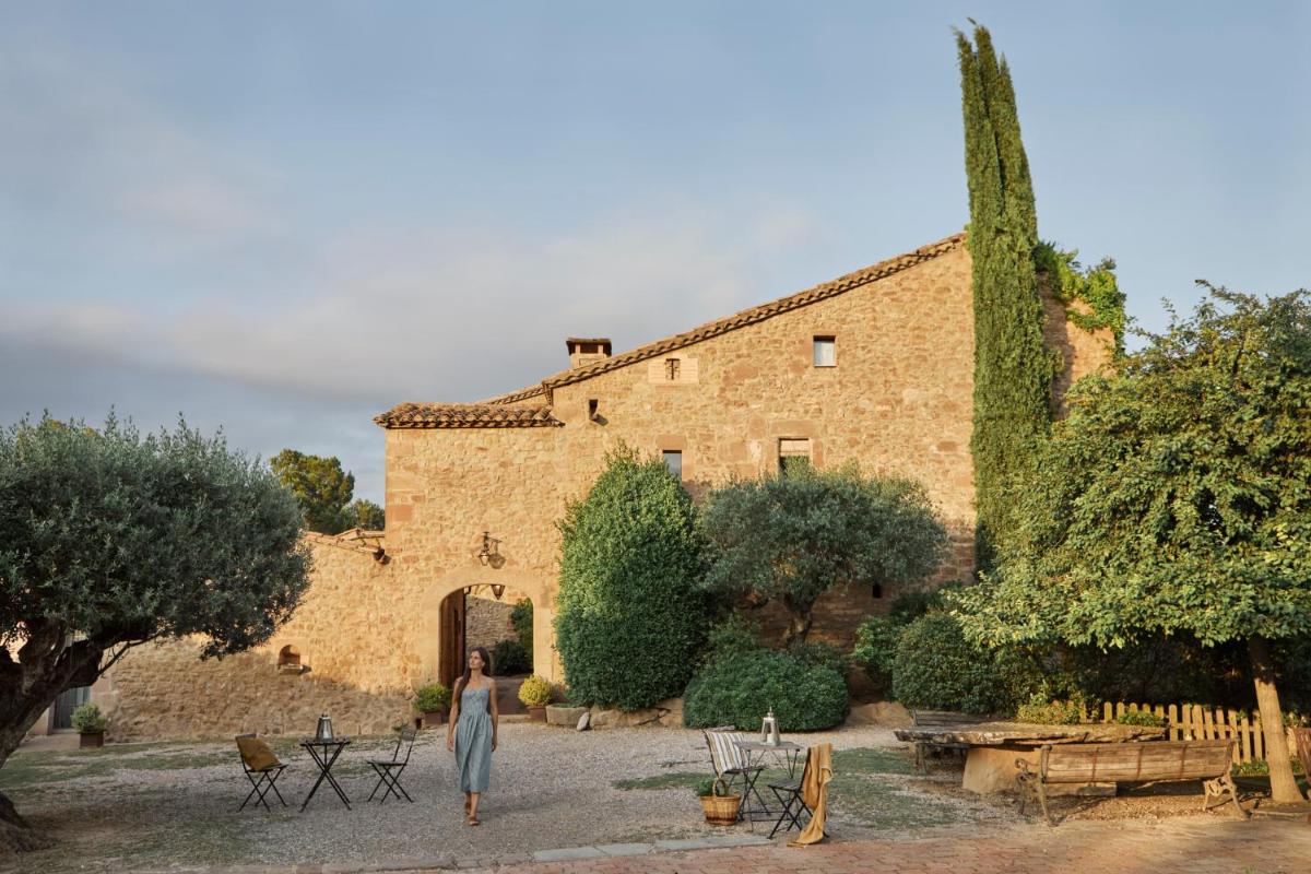 una mujer caminando frente a un gran edificio de ladrillo en La Garriga de Castelladral, en Castelladral