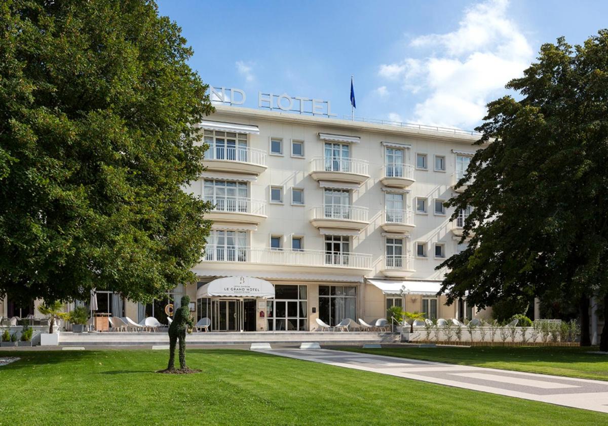 un grand bâtiment blanc avec une statue devant lui dans l'établissement Hôtel Barrière le Grand Hôtel Enghien-les-Bains, à Enghien-les-Bains