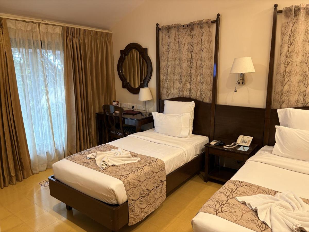 a hotel room with two beds and a desk at The Crown Goa in Panaji