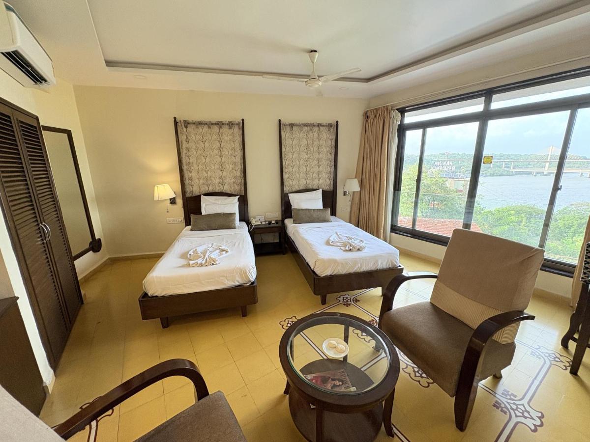 a hotel room with two beds and a window at The Crown Goa in Panaji