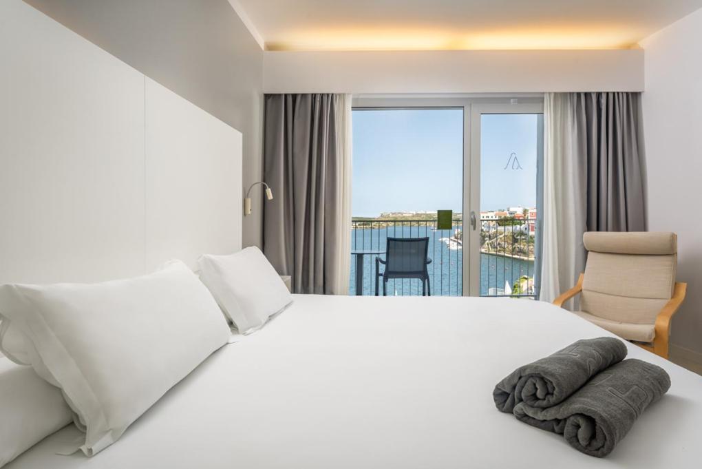 Un dormitorio con una cama blanca y una ventana grande. en ARTIEM Carlos - Adults Only, en Es Castell