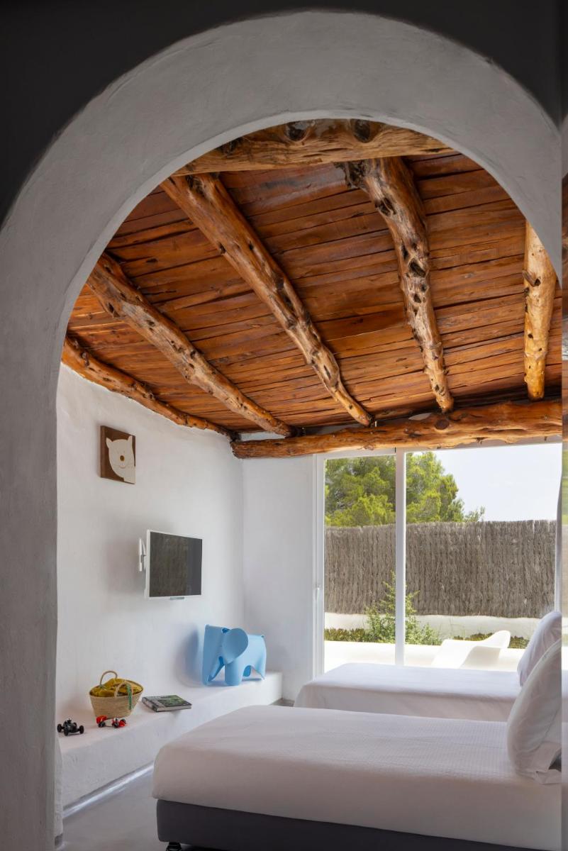 Un dormitorio con una cama y una ventana grande. en Hacienda Na Xamena, Ibiza, en Na Xamena
