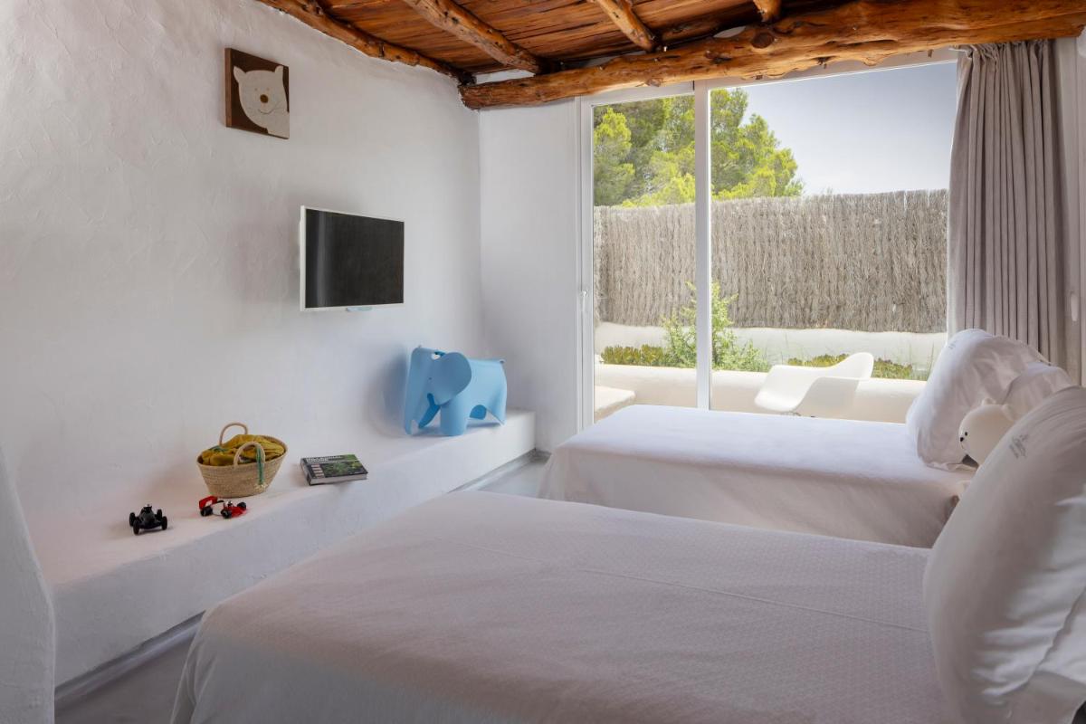 Dos camas en una habitación blanca con ventana. en Hacienda Na Xamena, Ibiza, en Na Xamena