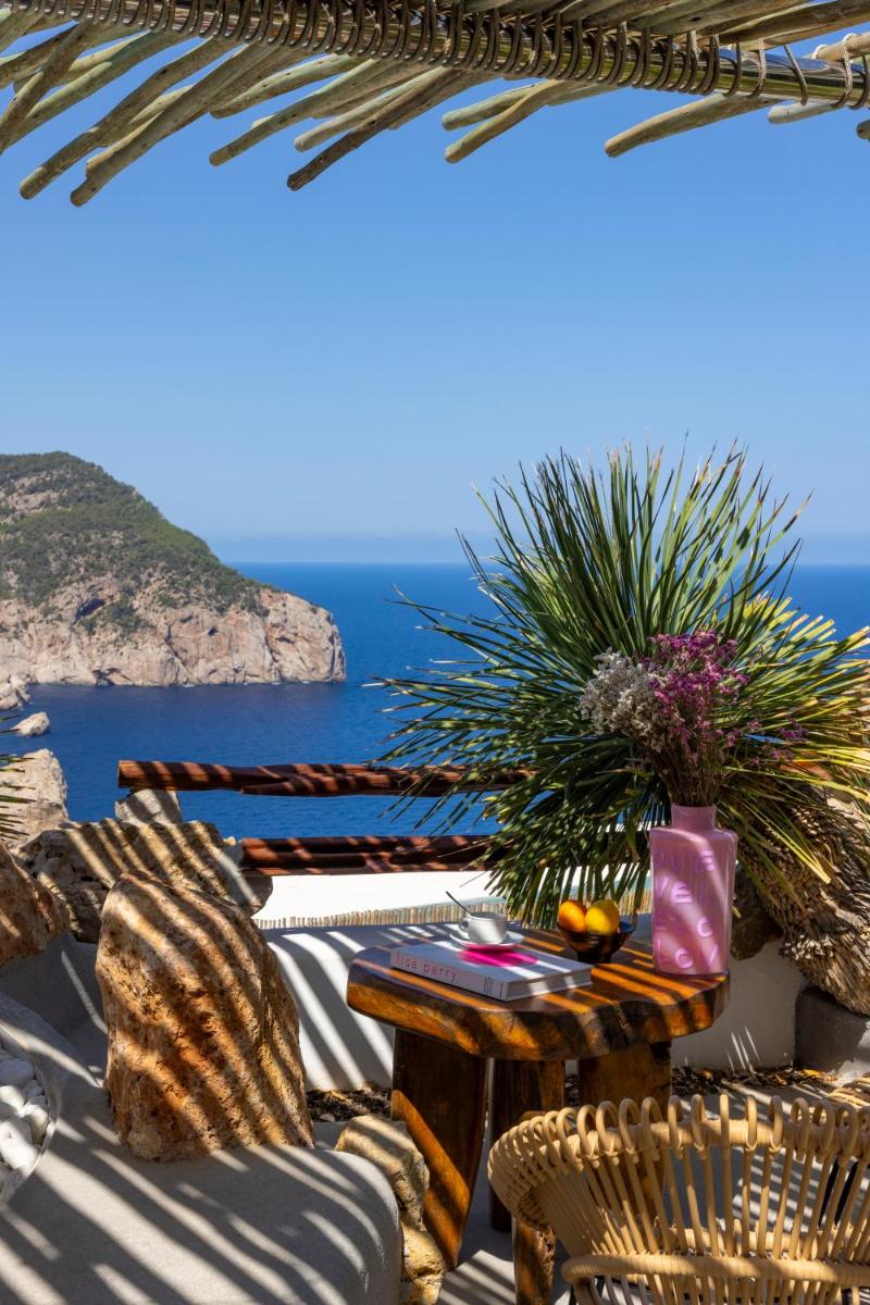 Un patio con mesa y sillas y el mar. en Hacienda Na Xamena, Ibiza, en Na Xamena